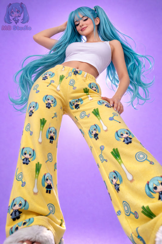 Low angle front view of yellow Hatsune Miku chibi pyjama bottoms with all over character and leek print, women’s anime fleece lounge trousers studio image