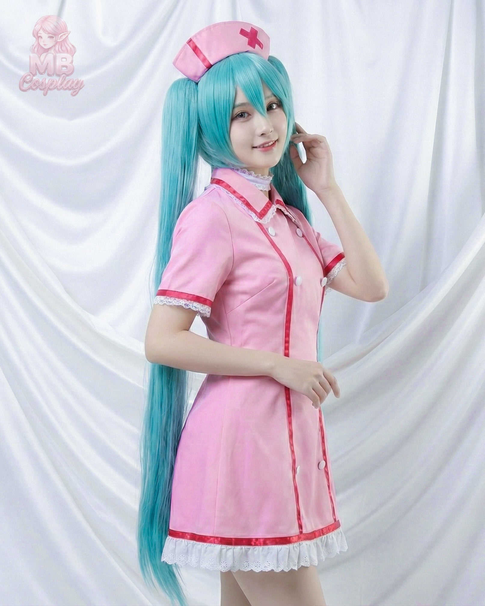 A cosplayer wearing the Hatsune Miku pink nurse outfit and long teal twin-tail wig, posing from a side angle against a white draped background
