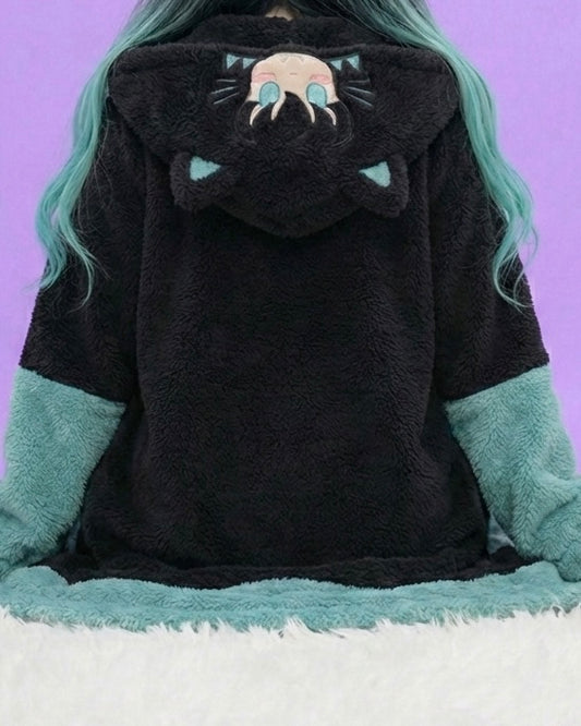 Black hoodie with cat face design worn by a person with teal hair against a purple background